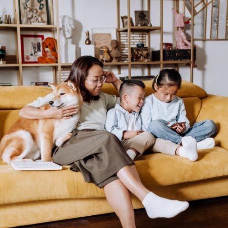 Familie mit Hund und Kindern entspannt auf dem Sofa