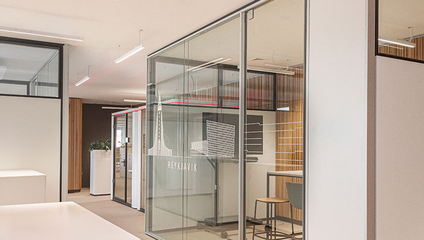 Eine Glastrennwand in einem Büro, die zwischen weiße Holzelemente gebaut wurde.