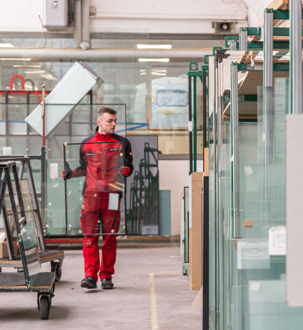 Ein Monteur beim Einräumen von unterschiedlichen Glasarten im Showroom von Glasbau Frommen.